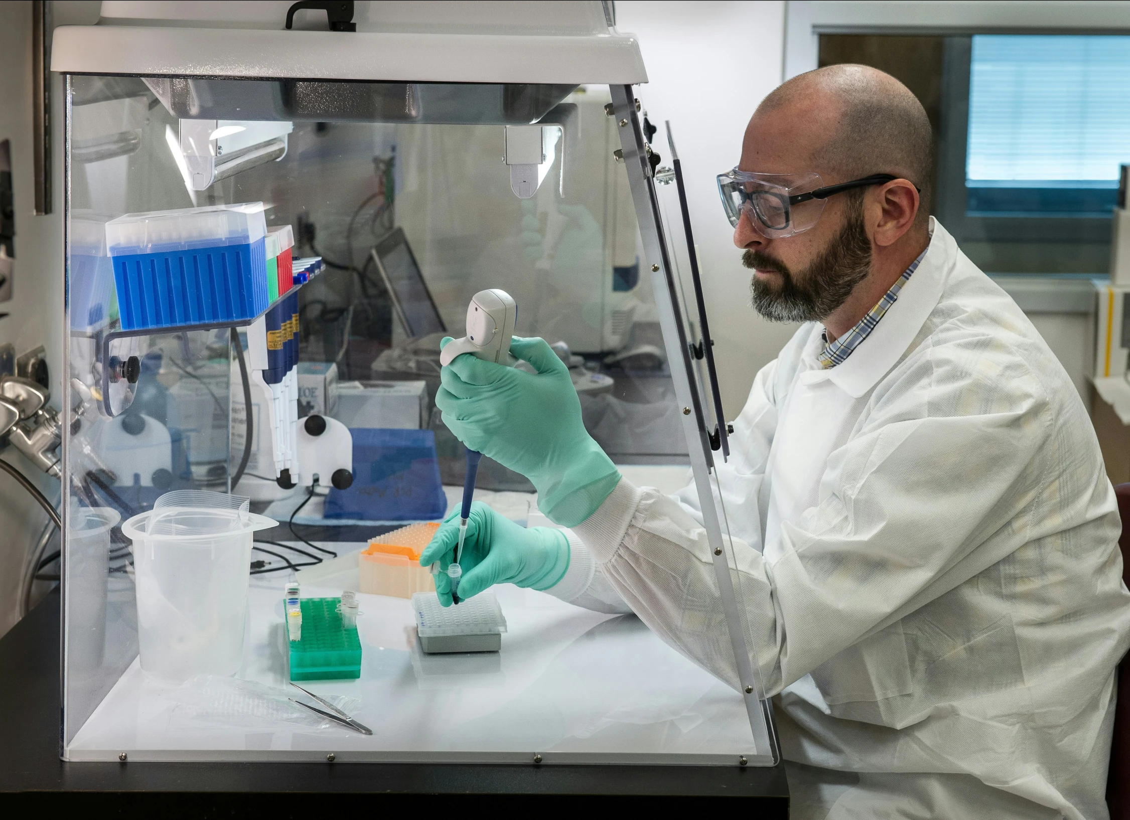 a male in a white coat and some green gloves