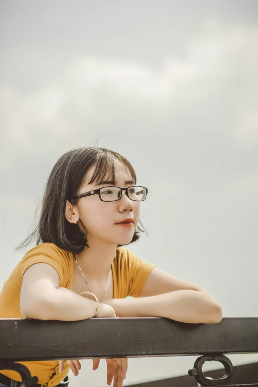 a woman with glasses and a t - shirt sitting on a bench