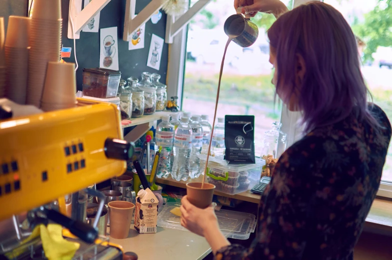 a woman is preparing a cup of tea inside a store