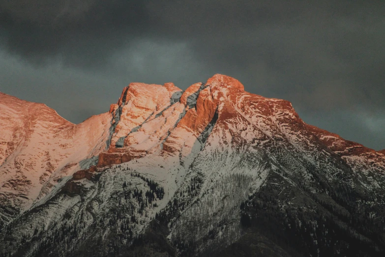 the tops of snow covered mountains with dark clouds