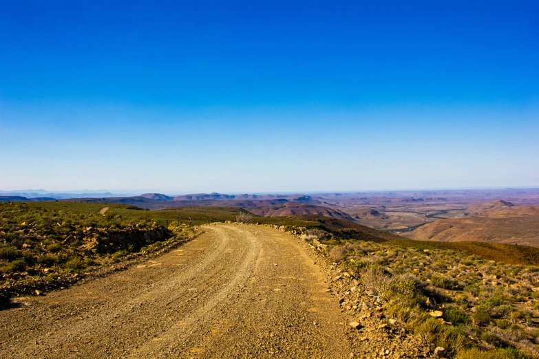 a dirt road on a hill overlooking mountains