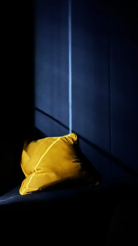 a small yellow pillow on a blue wall