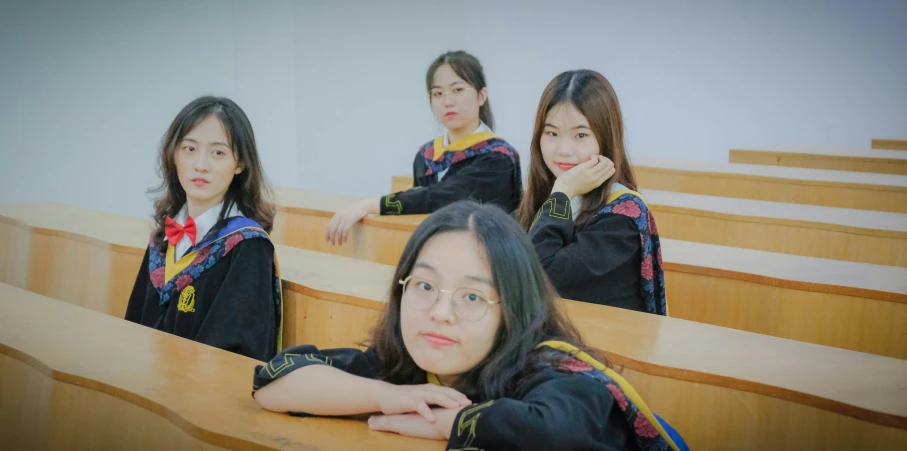 three asian girls are sitting in the seats of an empty classroom