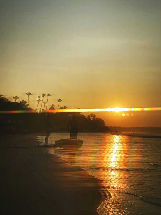 two people stand in the water at sunset