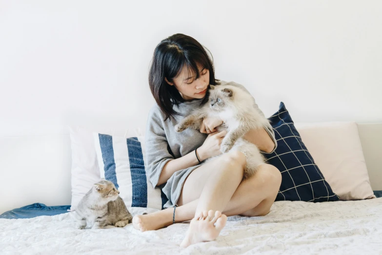 a woman sitting on top of a bed holding a dog