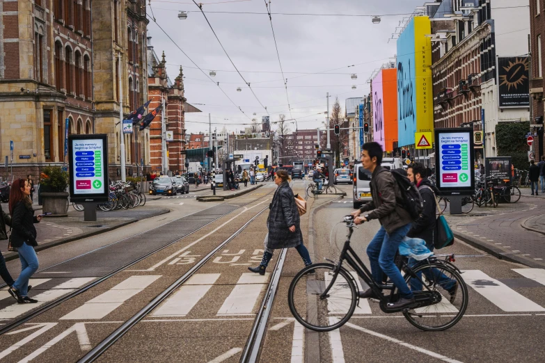 a man rides a bike down the street while pedestrians cross