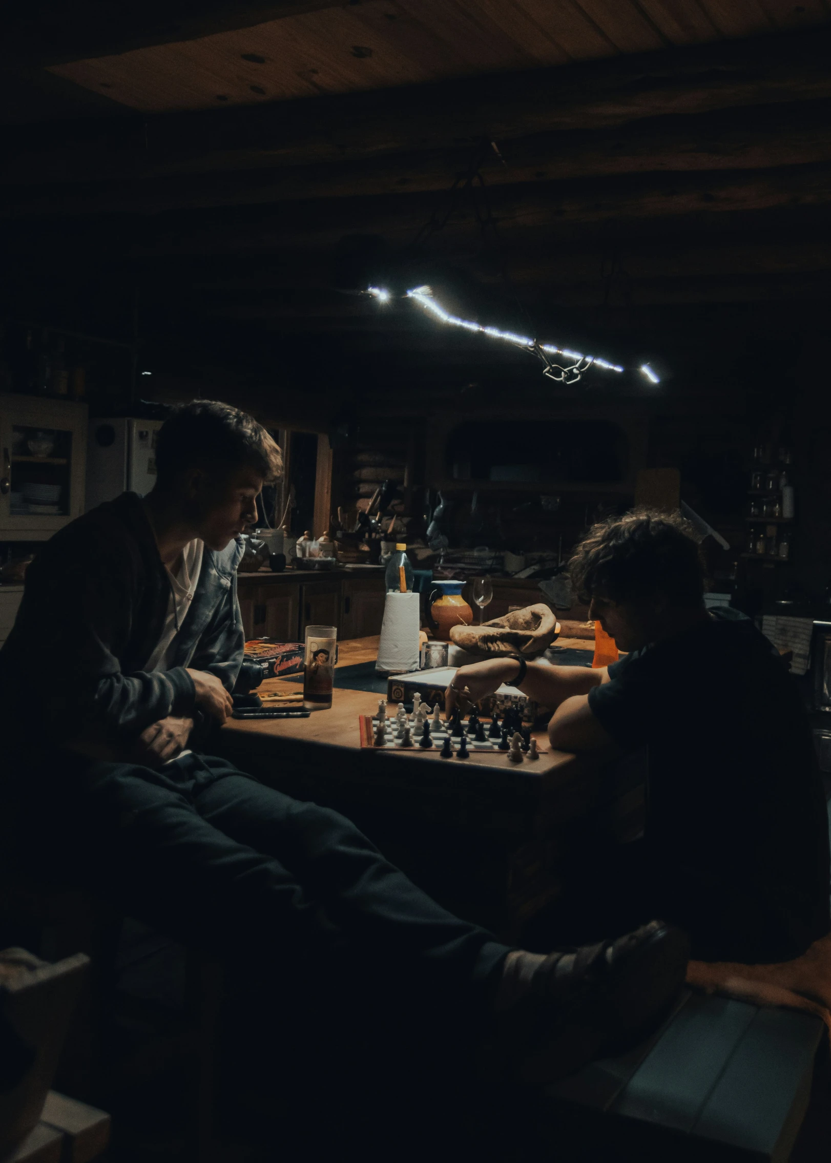 two men sitting at a wooden table playing chess