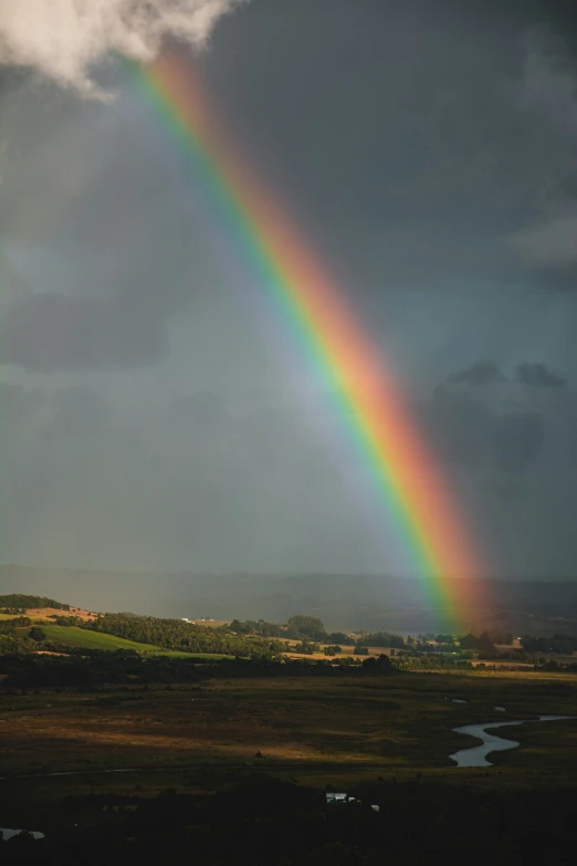 a rainbow shines brightly over the mountains and fields