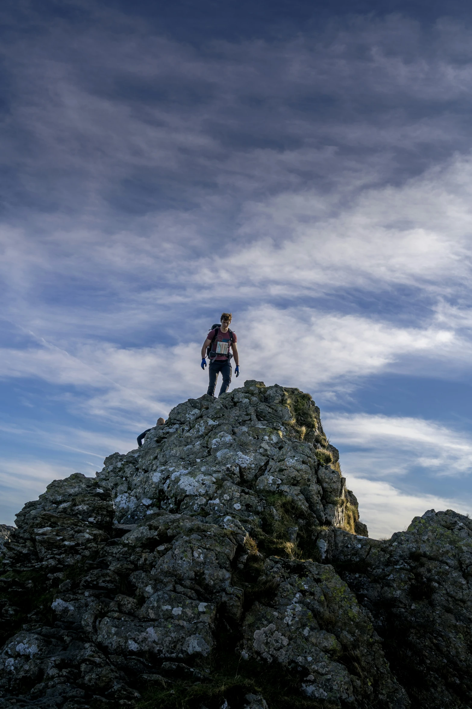 a man standing on top of a big rock on a mountain