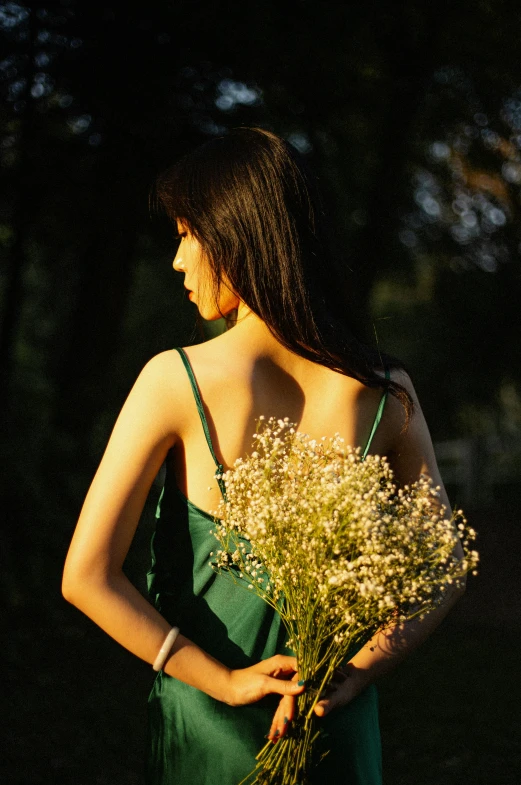 a woman in green dress standing behind flowers