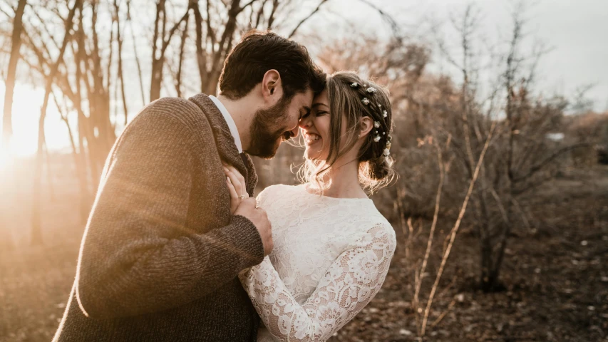 a couple poses in front of bare trees