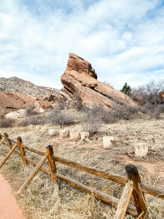 a brown wooden fence in the desert by some rocks