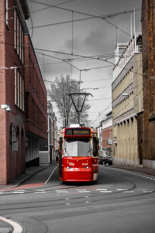 a red bus traveling down the street past tall buildings