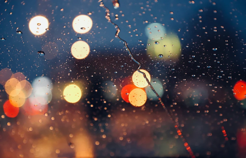 rain droplets on a window as cars are seen