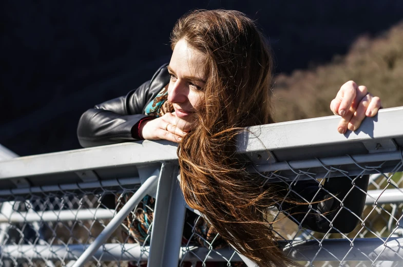 a young woman with long hair standing on top of a fence