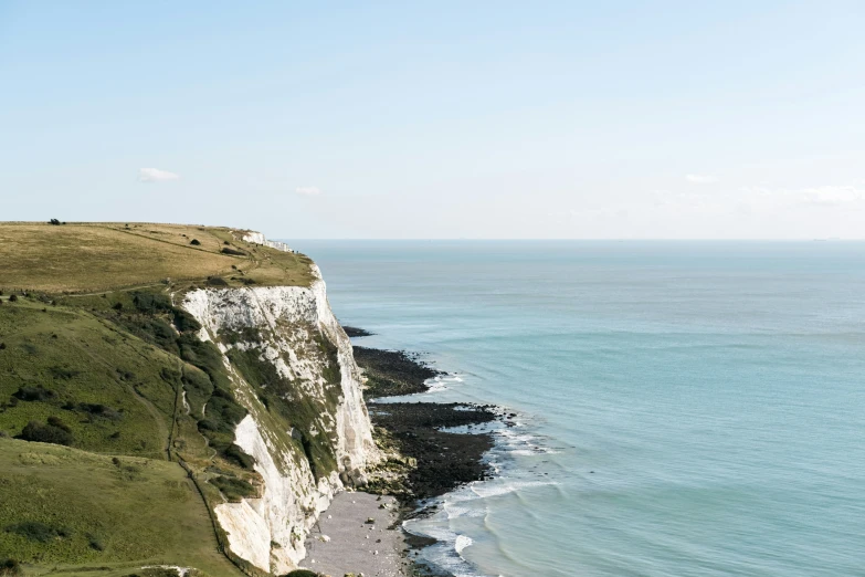 a cliff with white cliffs next to the ocean