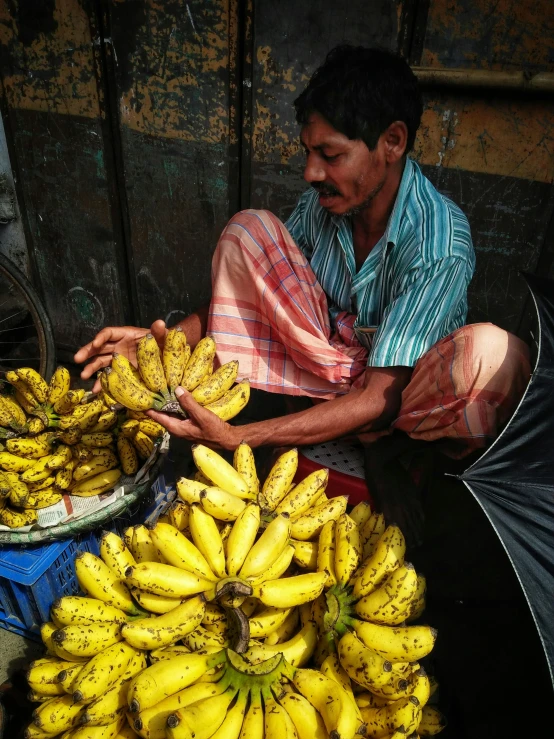 man with a lot of bananas at a market