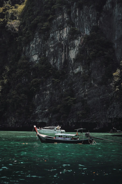 a boat floating down a river next to a hillside