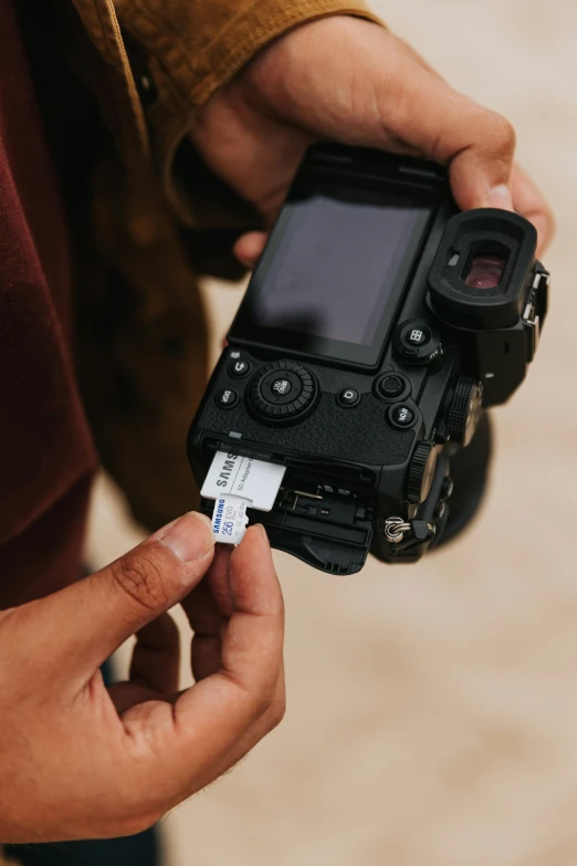 person holding a camera on top of a sandy beach