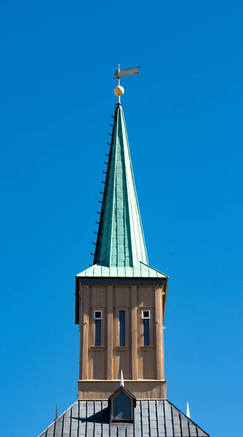 a tall spire with a clock on top and a cross on it