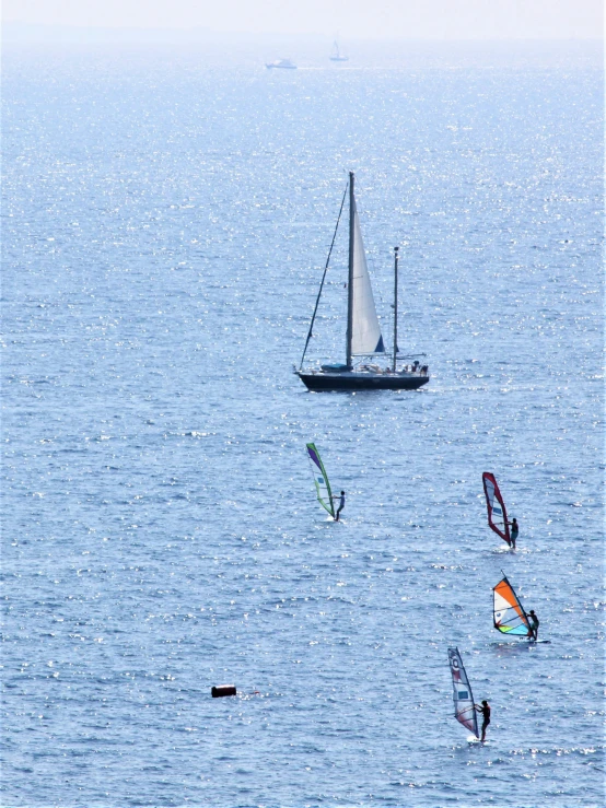 three windsurfers are sailing out on the ocean