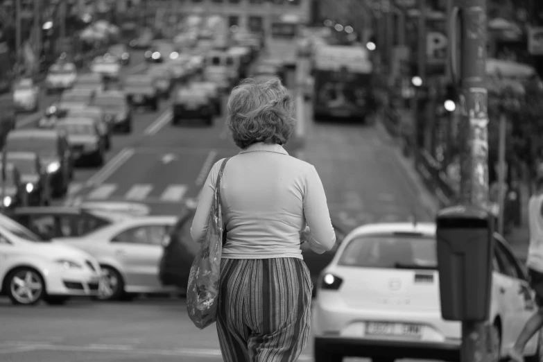 the woman is walking down the sidewalk with her luggage