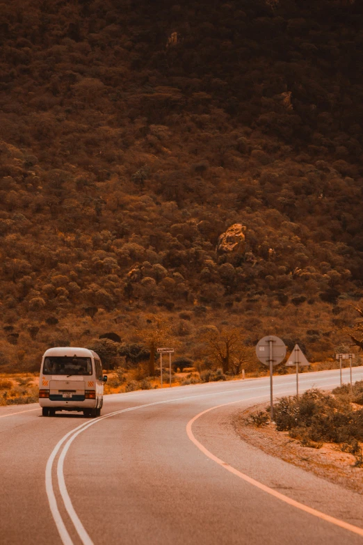 car moving through winding road near mountains under cloudy sky