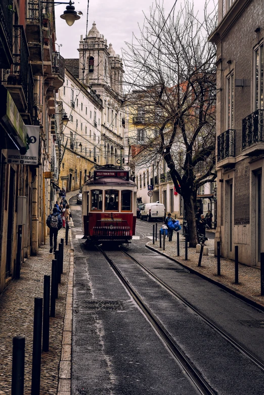a small trolley car rides down a narrow street