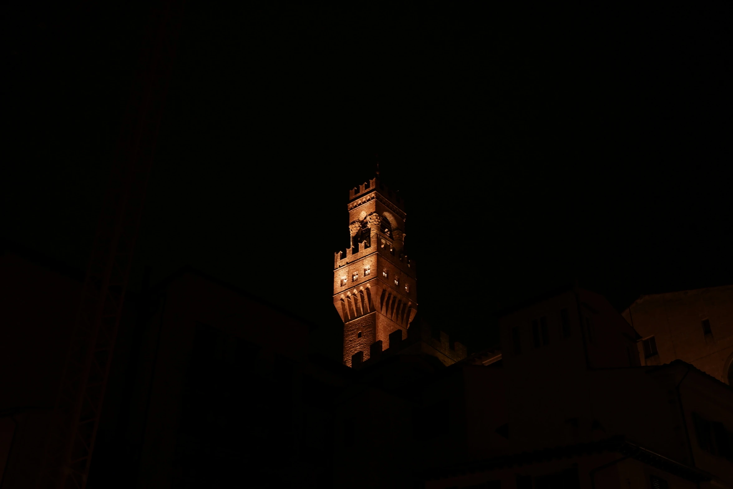 the clock tower is glowing from under a dark sky