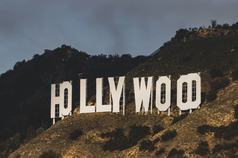 a sign with words that spell out hollywood on top of the hill