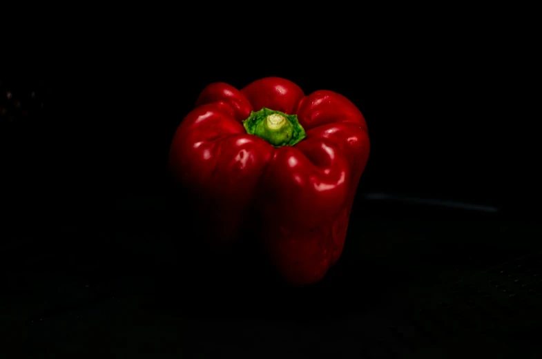 two red peppers in the dark on a counter