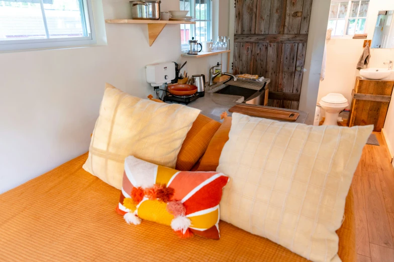 a bed topped with lots of pillows next to two windows