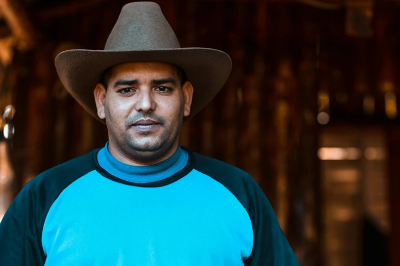 a man wearing a cowboy hat and standing in a barn