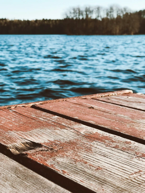 a dock on water near some trees and land