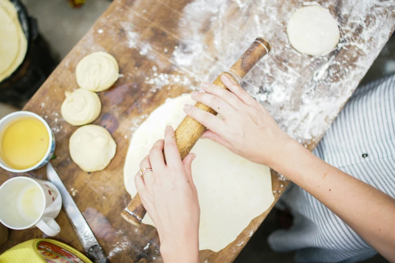 an image of someone's hand rolling out dough on a  board