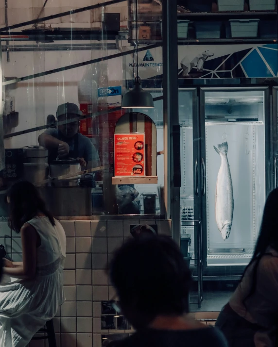 two people cooking a fish in an industrial kitchen