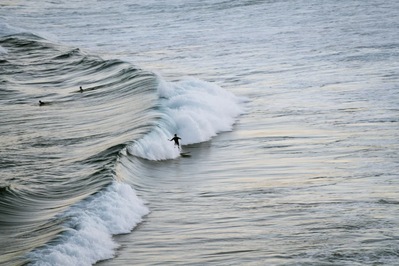 a surfer rides a wave as another surfer approaches