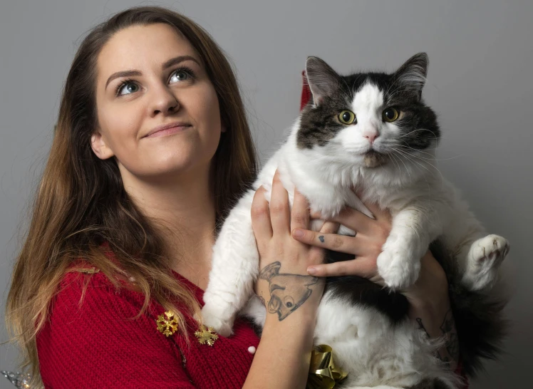 a woman holds a cat up in front of her