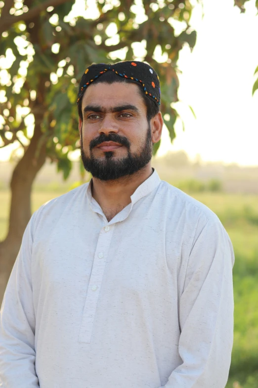 a man with a turban stands near a tree