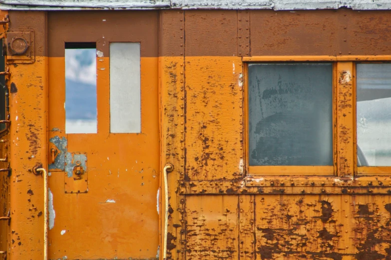 this is an old looking, rusty yellow door and window on a rusted train