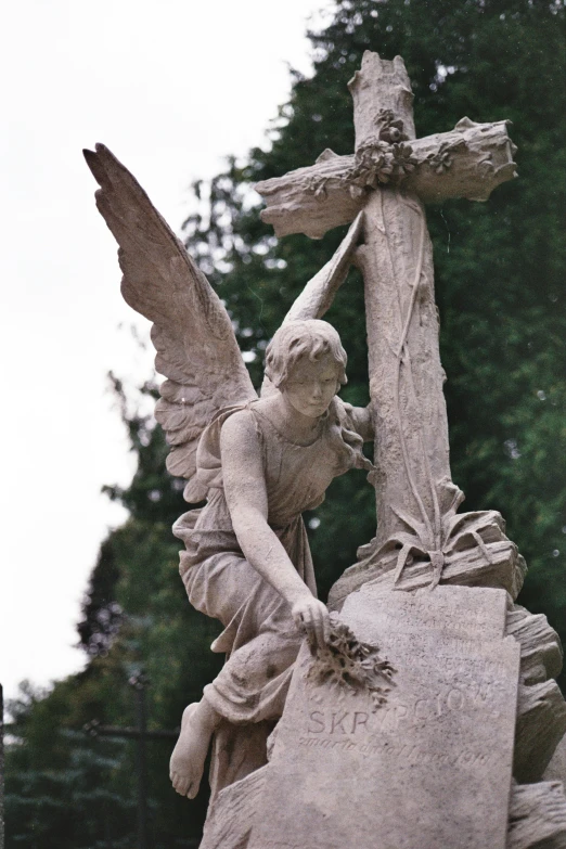 a statue of a person holding a cross with an angel flying nearby