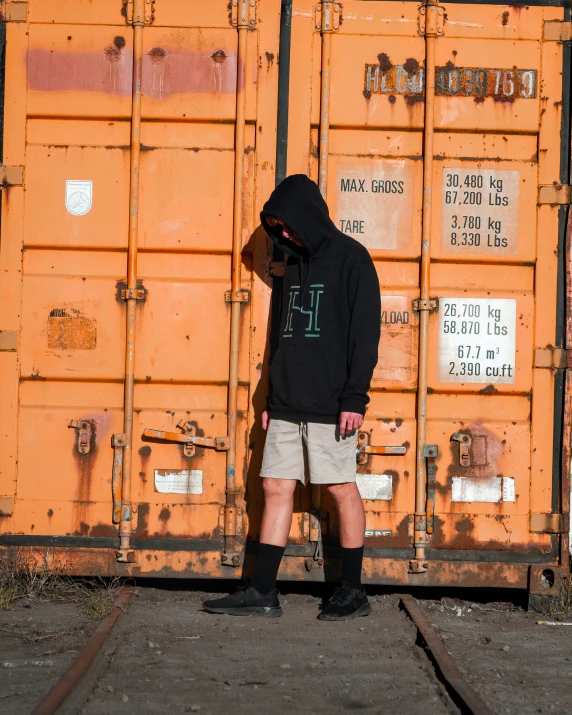 there is a person in black hoodie near a rusted container