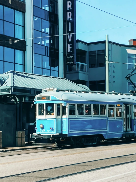 a blue train car next to a building