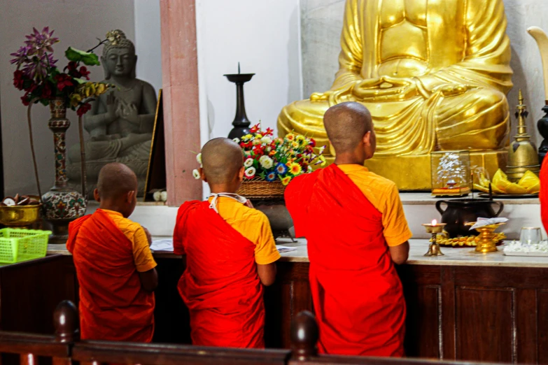 three buddhist monks are sitting in front of a golden statue