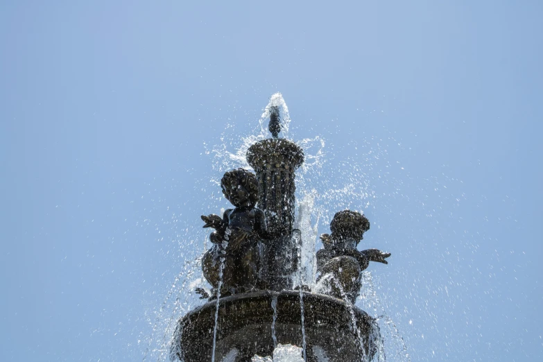 water spewing from fountain sculpture showing four children and one dog