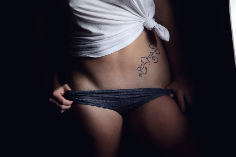 a woman's stomach with an underwiret tattoo on her bottom