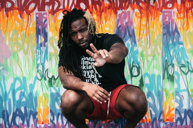 a man squatting down on his knees with one hand up in the air while wearing a bandana