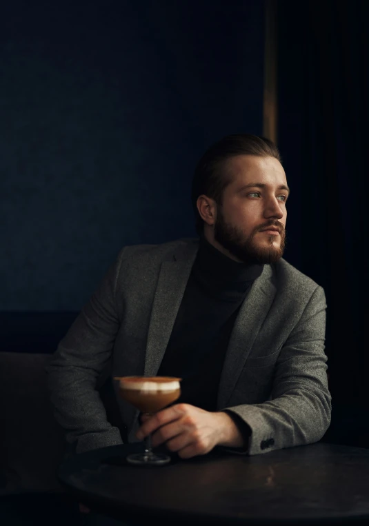 a man sitting at a table with a drink in his hand