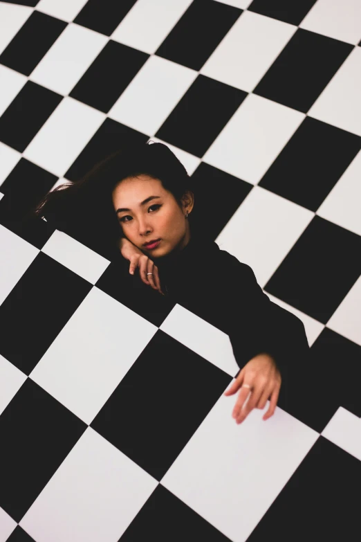 a woman sitting on the ground with her hand on a checkerboard floor