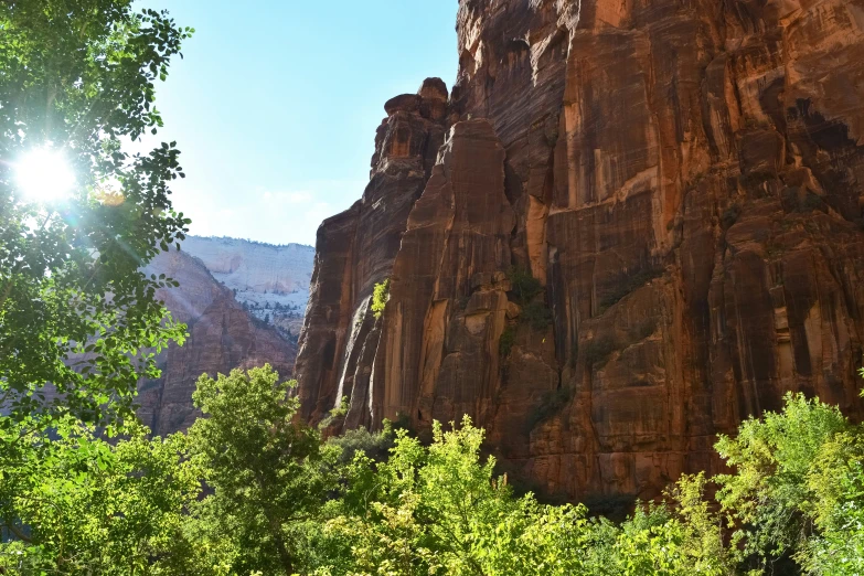 a sun shines in between some tall rocks